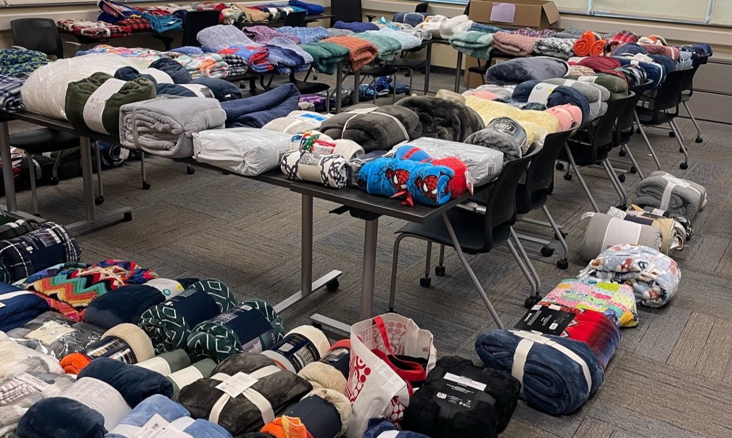 Conference room with 350 new packaged blankets lined up on tables, chairs, carts, and the floor.